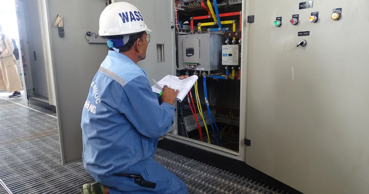 Technicien prenant des notes devant une armoire électrique